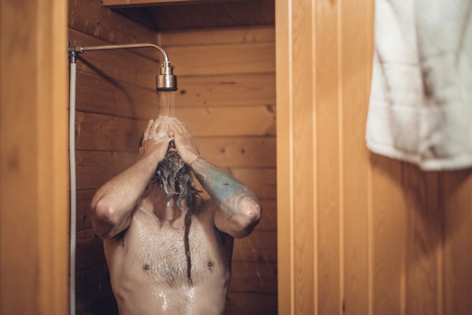Man taking shower in wooden bathroom