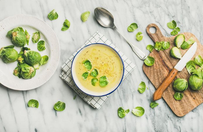 Brussels sprout soup, garnished with fresh sprouts, next to wooden board