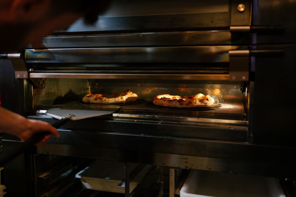 Pizza man checking pizzas in the oven