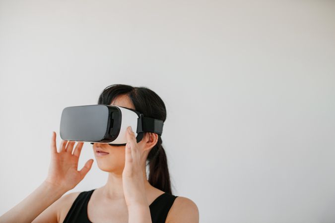 Shot of young woman in VR headset looking away at the objects in virtual reality