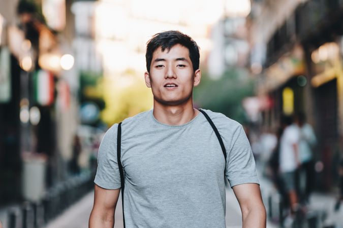 Confident Asian man walking along city street
