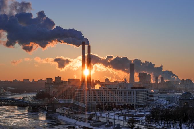 Factory with polluted air at sunset