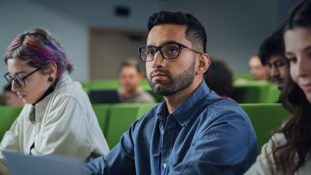 Young Male Student Studying in University with Diverse Multiethnic Classmates.