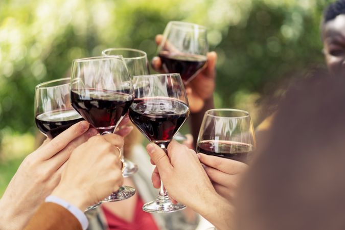 Close-up of friends toasting with red wine in an outdoor celebration
