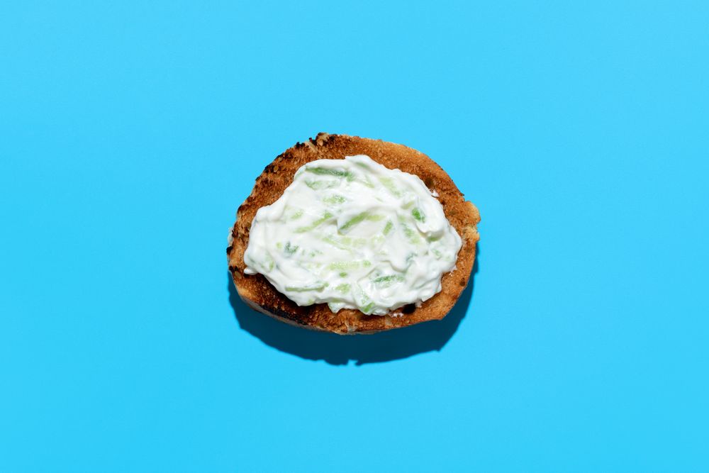 Tzatziki sauce on toasted bread, above view on a blue background