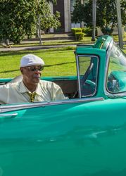 Havana, Cuba - November, 22 2012: Black man sitting in retro car on street