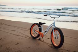 Modern fat bicycle parked at beach on sunset