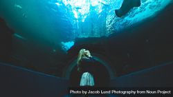 Woman standing in a walkway underwater in a aquarium 49OKy0