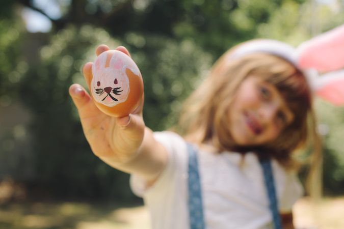 Smiling girl holding a painted easter egg in her hand