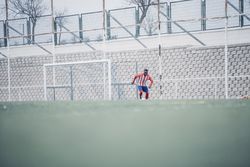 Black soccer player with red equipment playing soccer.