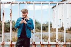 Man using smartphone near rusty fence