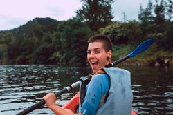 Female kayaking with paddle in raised hands
