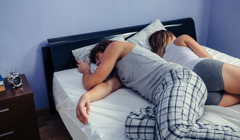 Couple sleeping back to back without sheets