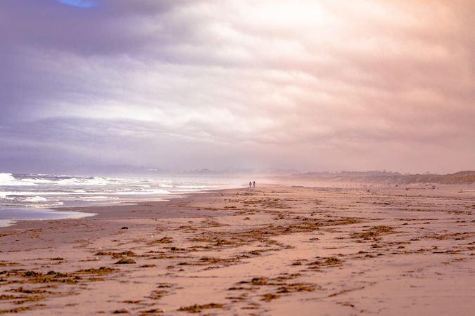Two people in the distance on quiet beach