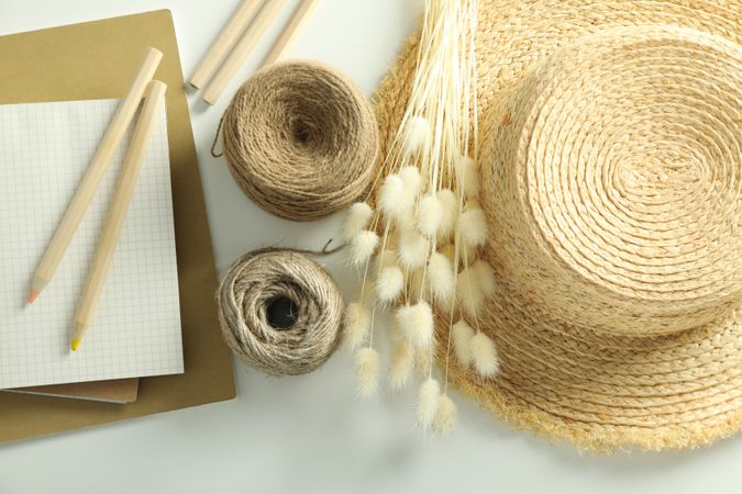 Looking down at table of arts and crafts supplies with note book and hat