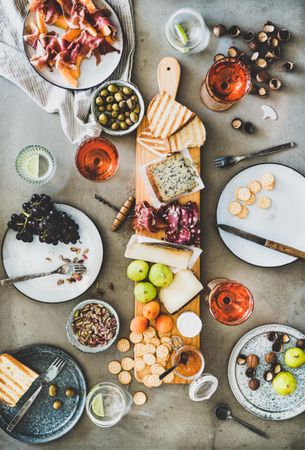 Charcuterie board with rose wine, hazelnuts, crackers, cheese, prosciutto, melon, grapes