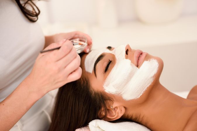 Woman applying facemask to client