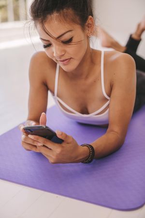 Female relaxing on floor after workout with a mobile phone