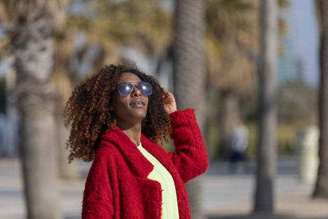 Serious female enjoying the sun on street with palm trees