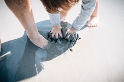 Child with parent kneading sand with hands and feet