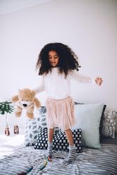 Little girl jumping on a bed