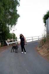 Full length shot of woman standing in street with her dog on a leash