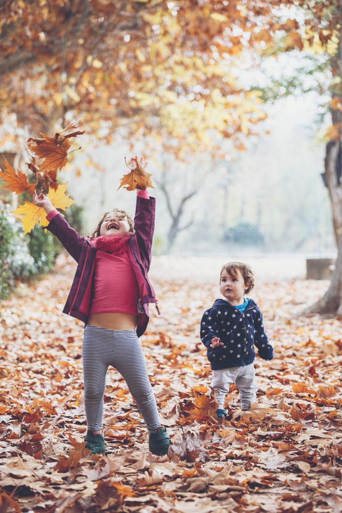 kids playing with leaves in autumn park