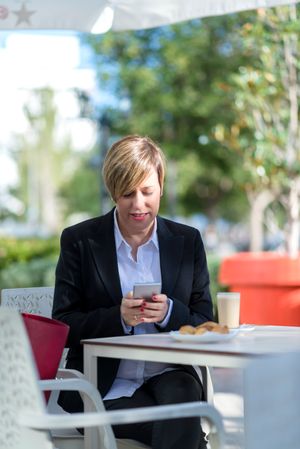 Woman having lunch on table outside checking phone