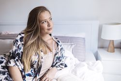 Woman relaxing in robe sitting on bed