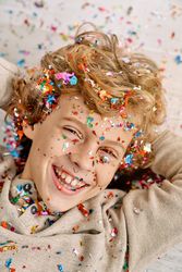 Cheerful fair haired boy in confetti