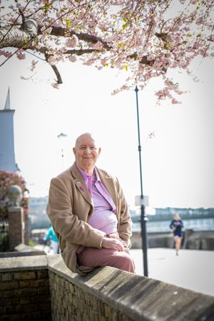 Smiling mature man sitting on wall near river