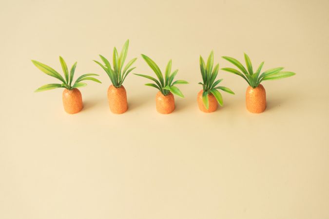 Row of carrots on pastel yellow background