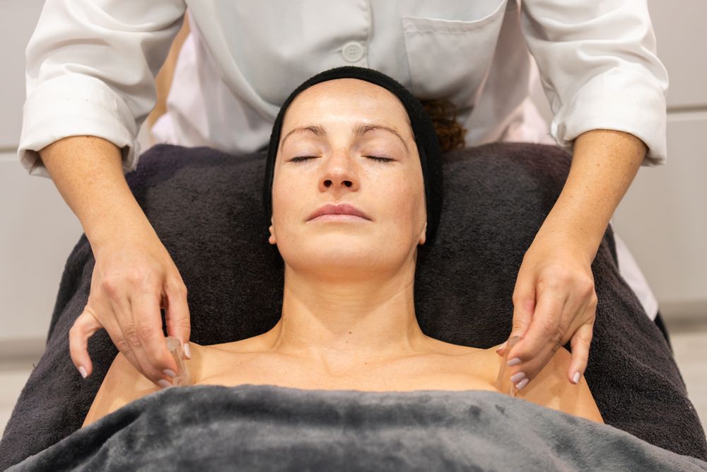 Female beautician massaging shoulders of client with stones