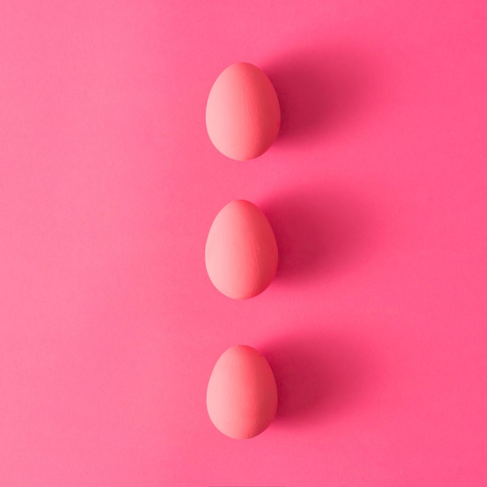 Row of three pink Easter eggs on pink background