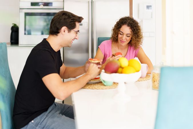 Happy couple eating delicious breakfast in bright kitchen