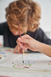 Unrecognizable kid painting near boy at table