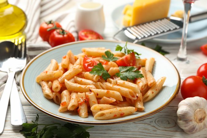 Composition with plate of tasty pasta and ingredients for cooking on wooden background