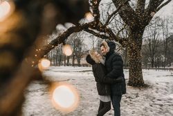 Smiling couple having fun on street near tree with fairy lights