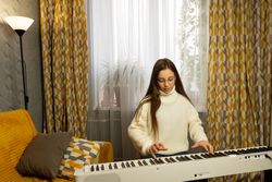Focused girl playing digital piano in cozy home environment.