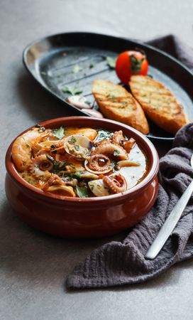 Soup of octopus and shrimps near toasts and spoon