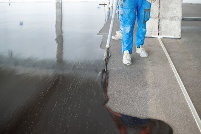 Crop masters pouring liquid concrete on floor at construction site