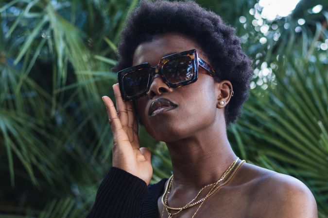 Confident Black woman in sunglasses against greenery