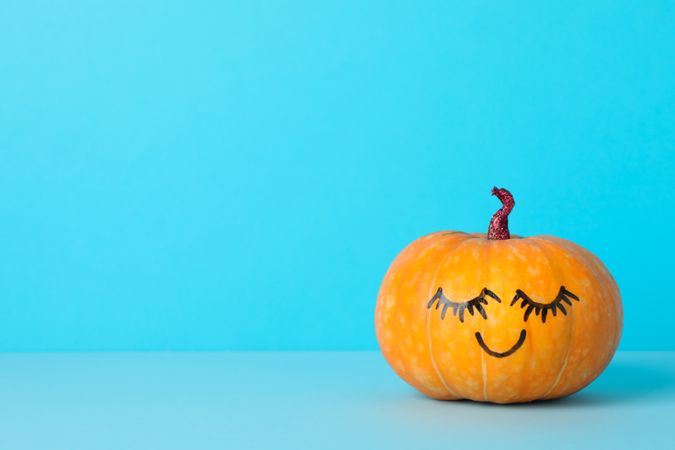 Pumpkin with smile on blue background, space for text