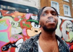 London, England, United Kingdom - August 28, 2022: Man exhaling smoke in front of graffitied wall