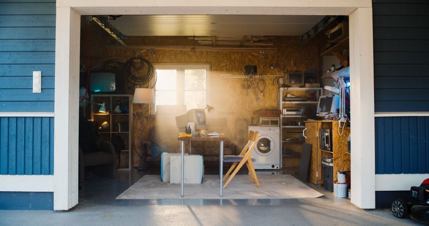 Establishing Shot Of Empty Workplace With Old Desktop Computer In Retro Garage With Random Home Appliances.