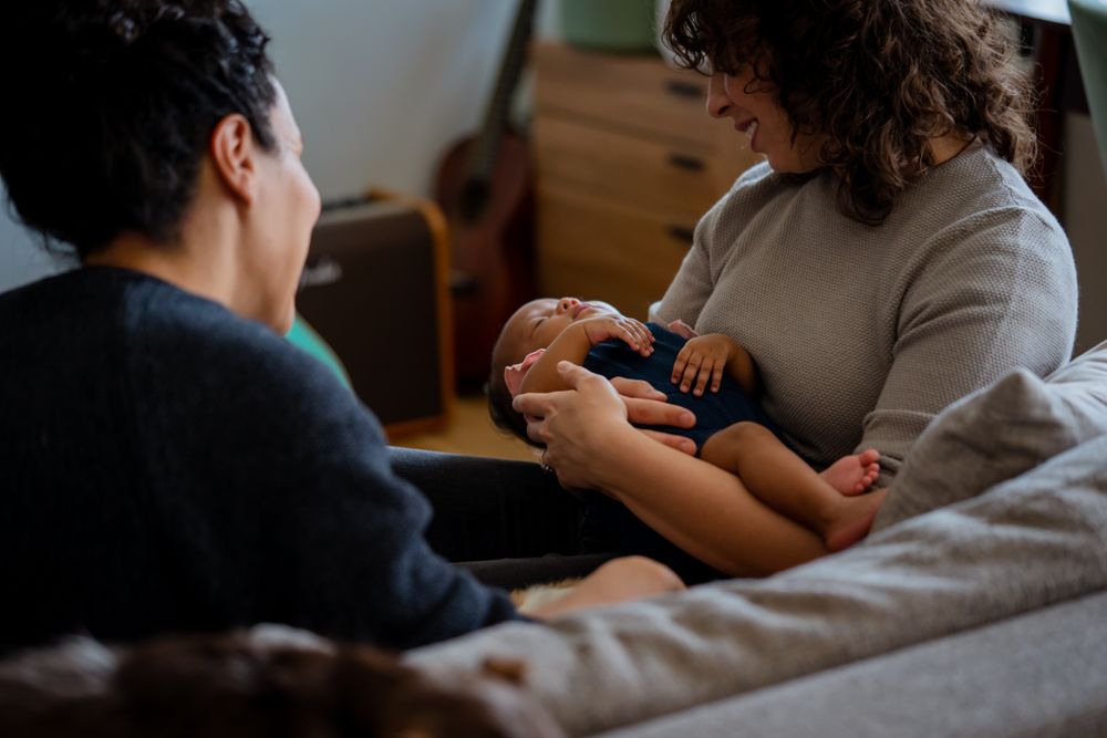Loving female couple rocking baby to sleep on sofa
