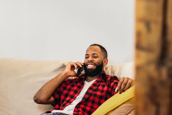 Black man making a call with smartphone relaxed at home