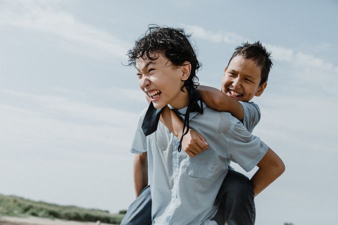 Happy boy in piggyback ride over back of brother