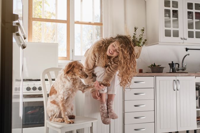Happy woman with dog in kitchen