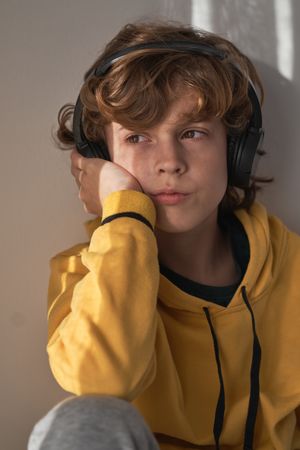 Dreamy boy in headphones looking away at home